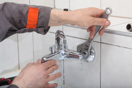 Plumber fixing water tap with spanner